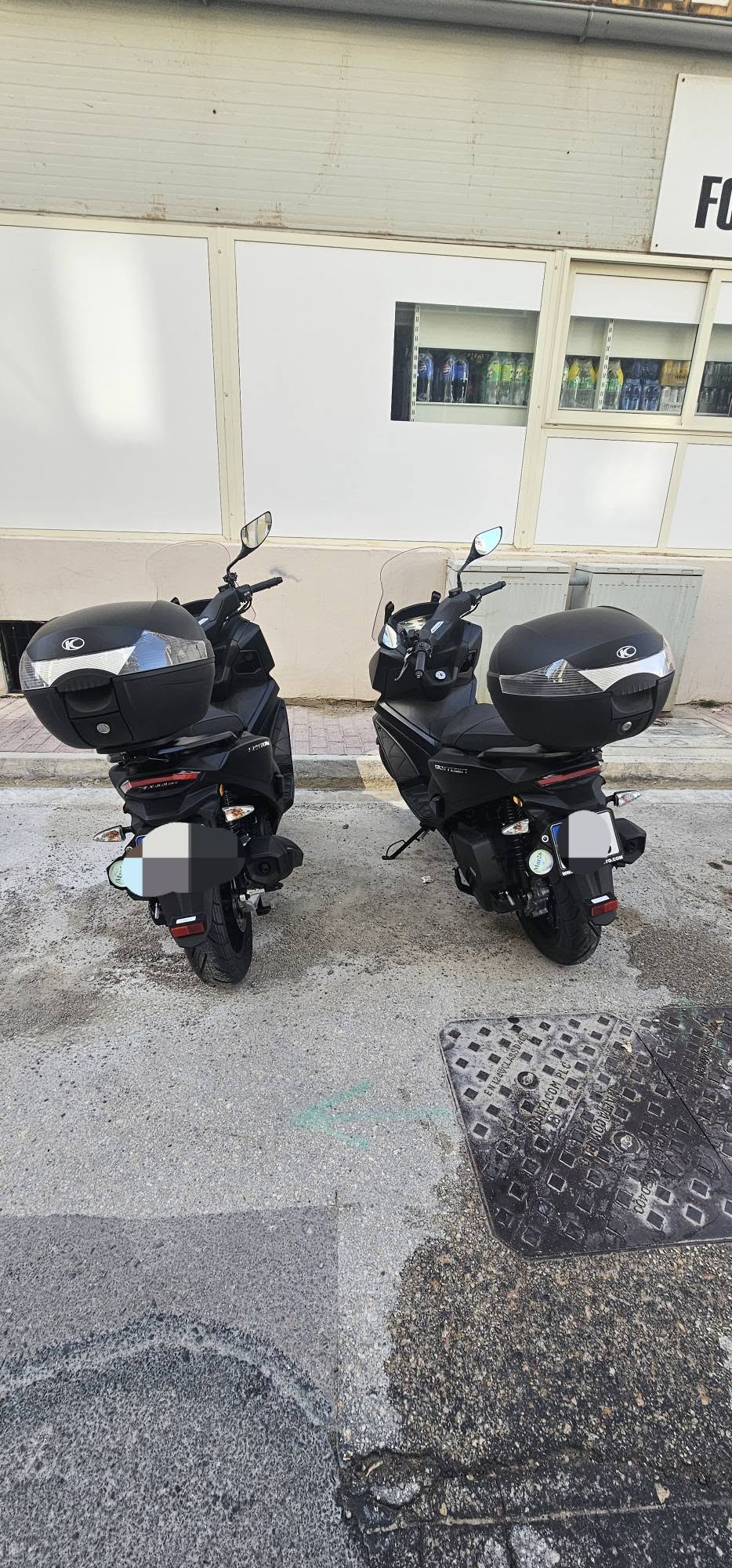 Two Kymco 125cc scooters with top boxes, parked